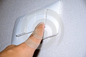 Man hand is turning on or off electrical light switch