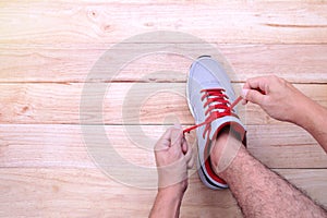 Man hand tying laces of running shoes before training on woode