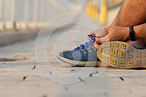Man hand tying sport shoe laces in casual clothes after workout..Young fitness man running outside city. People fitness, exercise.