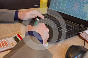 Man hand using calculator and writing make note with calculate about cost at home office. The Man and computer are using a calcula