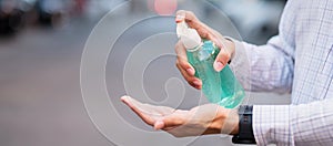 Man hand using wash hand sanitizer gel dispenser, against Novel coronavirus or Corona Virus Disease Covid-19 at public outdoor.