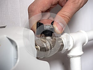 A man hand on the valve of the central heating battery. The concept of heat overlap, the crisis of energy carriers