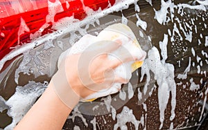 Man hand washing Brown Car with yellow sponge and bubbles