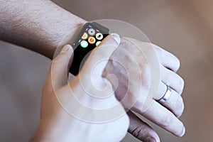Man hand wearing modern smart watch with cloud of apps on the screen. Wearable gadget concept.