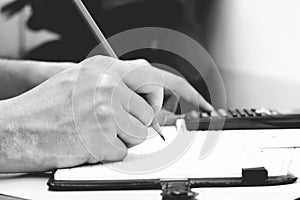 Man hand is writing in a notebook and calculator counting making