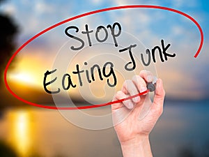 Man Hand writing Stop Eating Junk with black marker on visual sc