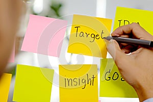 Man hand writing target word on sticky note at office, business brainstorming creative ideas, office lifestyle, success in