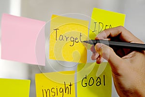 Man hand writing target word on sticky note at office, Close up of target and business idea words on adhesive note, Brainstorming