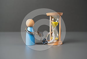 A man is handcuffed to an hourglass. photo
