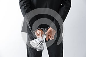 Man in handcuffs holding bribe money on background, closeup