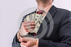 Man in handcuffs holding dollar banknotes isolated, close up