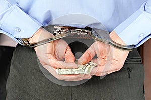 Man in handcuffs holds money in his palms behind his back