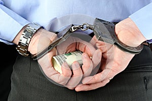 Man in handcuffs holds money in his palms behind his back