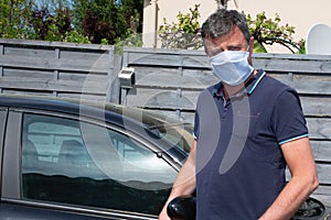 Man in hande made medical mask respirator gets out of van car during coronavirus epidemic covid-19