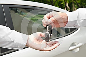 Man handing another person automobile keys new car