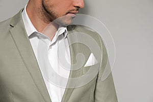 Man with handkerchief in breast pocket of his suit on grey background, closeup