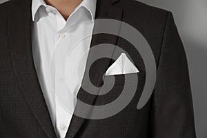 Man with handkerchief in breast pocket of his suit on light grey background, closeup