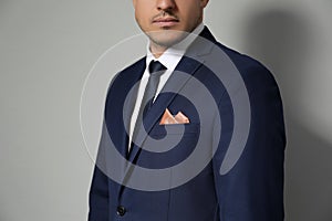 Man with handkerchief in breast pocket of his suit on light grey background, closeup