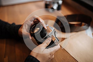 Man hands adjusts the lens retro camera on a wooden table