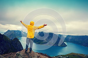 Man with hands in the air standing on a cliff of mount Reinebringen