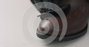 Man hands in black gloves applying protective cream to brown leather chukka boots