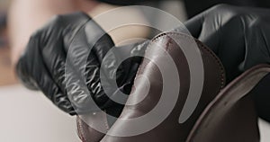 Man hands in black gloves applying protective cream to brown leather chukka boots