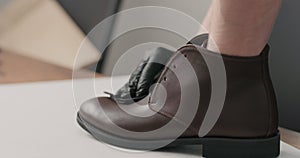 Man hands in black gloves applying protective cream to brown leather chukka boots