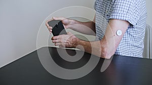 A man hands brings to the hand the smartphone for measuring glucose in the blood