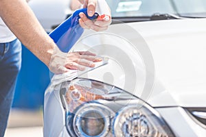 Man hands cleaning and spaying modern white car