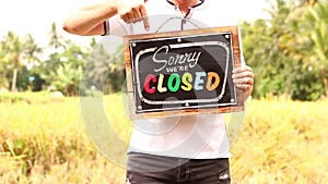 Man hands with closed sign board on a tropical nature background. Bali island.