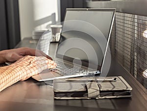 Man hands closeup typing on laptop keyboard. Bisinessman, freelancer or student sitting at cafe table with notebook and