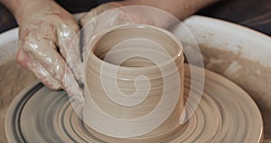 Man hands creating jar or vase of white clay. Twisted potter`s wheel. Handmade, craft