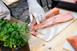 Man hands cutting pink raw salmon with knife on board