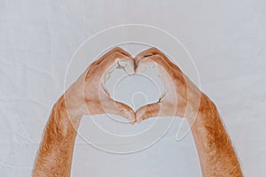 Man hands dirty of clay making heart shape on white background