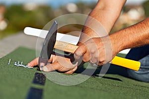 Man hands fastening bitumen roof shingles photo