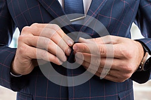 Man hands fastening business suit jacket button
