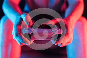 Man hands with game controller in neon light, front view