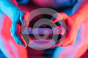 Man hands with game controller in neon light, front view