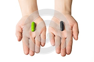 Man hands giving two big pills. Green and black. Make your selection. health or death. Choose your side