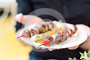 Man hands with gourmet street food- ostrige meat skewers