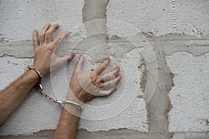 Man hands in handcuffs with spread fingers on a grey wall background. Arrested criminal. Copy space, Moc up