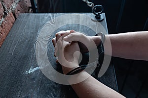 A man with hands in handcuffs at table
