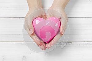 Man Hands Hold Pink Heart on white wood background. Giving love concept