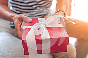 Man hands hold red gift box toward front. Valentines gift box. Season greeting