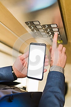 Man hands holding blank screen mobile phone while using elevator control panel