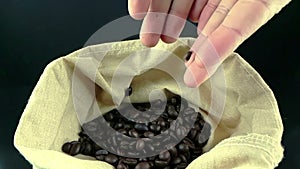 Man hands holding coffee beans in canvas sack and some falling down, shot slow motion, agriculture and nutrition