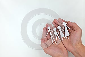 Man hands holding a family paper cutout in white background. Family care, protection and planning