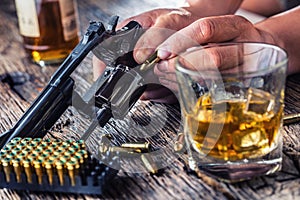 Man hands holding gun and alcohol glass on the table