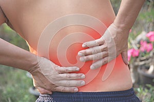 Man with hands holding his waist back in pain. A man pain concept with red spot.