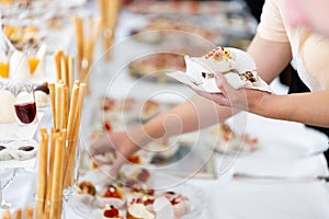 Man hands holding plate and picking up canapes appetizers from buffet table on event